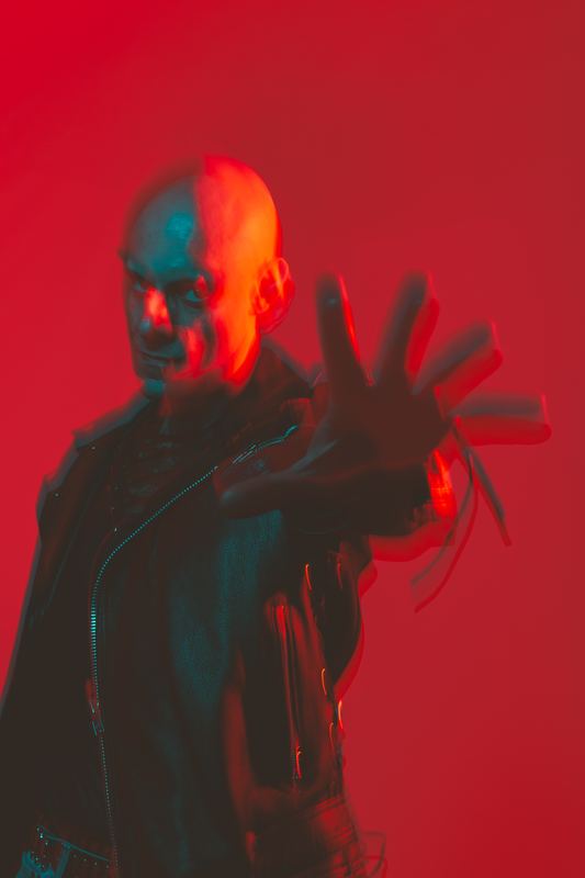 Portrait on red, a musician pushing his hand toward the camera