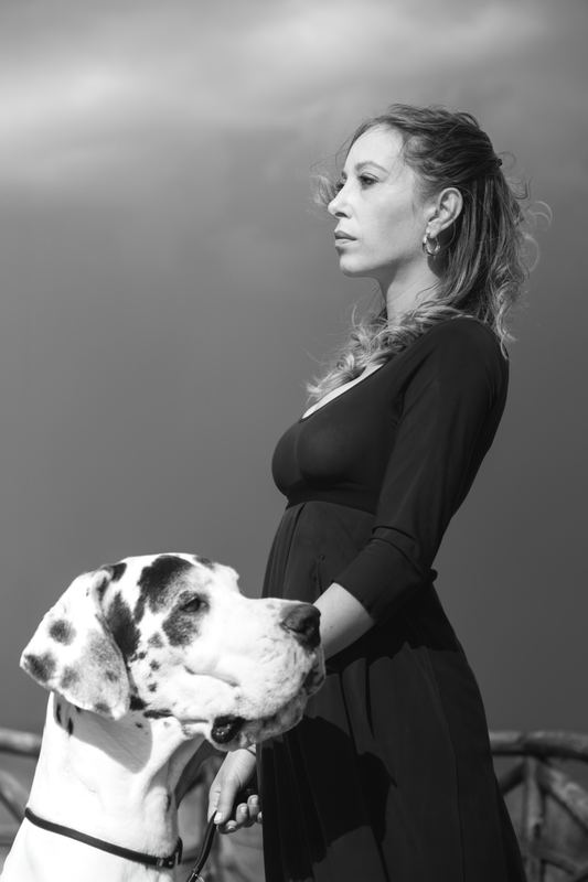 Black and white portrait of a pregnant woman with a Great Dane, outdoors