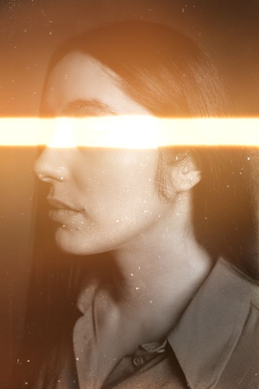 A woman's profile crossed by a blade of orange light, sepia tones