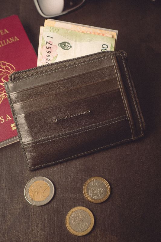 Leather card wallet and coins on dark wood, close-up product photography